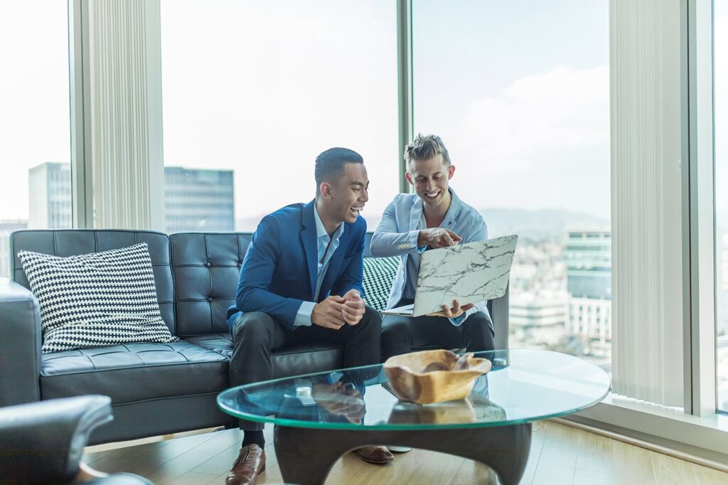 Two men sitting on couch looking at a laptop