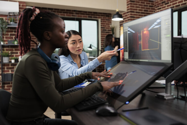 Two women collaborating in front of a computer workstation